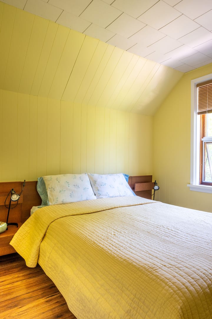 Habitación amarilla con cama tamaño queen.