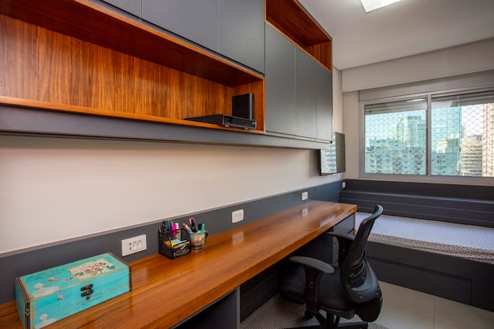 Moderná izba kombinuje funkčnosť a štýl s veľkou drevenou pracovnou doskou, elegantnými skrinkami a prirodzeným osvetlením. Vstavaná posteľ pridáva praktickosť, vďaka čomu je ideálnym priestorom na štúdium, prácu alebo oddych s úžasným výhľadom.