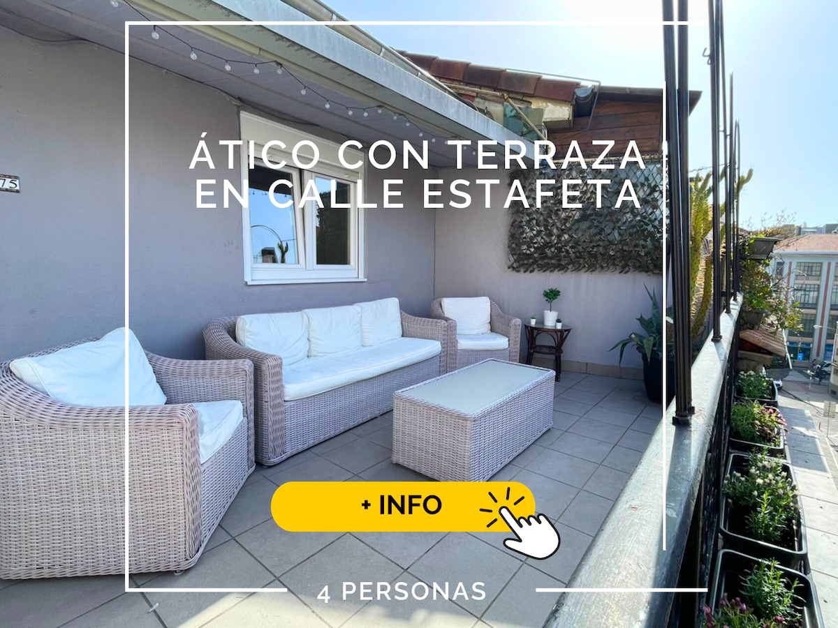 A spacious terrace features outdoor seating, including a wicker sofa, a small table, and a decorative accent table. The area is well-lit by natural light, and potted plants add a touch of greenery, creating a welcoming outdoor space for relaxation.