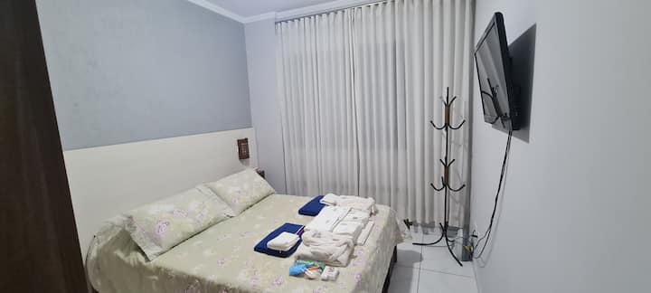quarto com cama de casal com mesas de cabeceira e luminárias , gaveteiros sob a cama, onde você  vai encontrar tábua de passar e ferro à vapor. Aquecedor, ventilador de teto com controle remoto e luz regulável. TV com canais abertos.