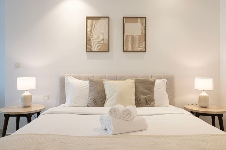 A cozy bedroom with a large bed, white comforter, and neatly arranged pillows. 