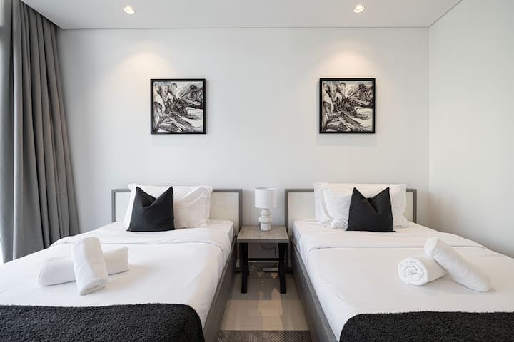 Step into a chic, contemporary and spacious bedroom featuring two beds A modern desk, complete with an lamp this adds a touch of sophistication. Artful decor enhances the walls, while a large window guarantees stunning Dubai Downtown skyline views.