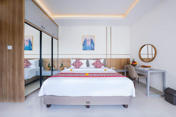 The bedroom offers a spacious and cozy retreat, featuring a comfortable king-size bed, air conditioning, a safe deposit box, a wardrobe for ample storage, and a desk with a chair, providing both convenience and comfort for a relaxing stay.