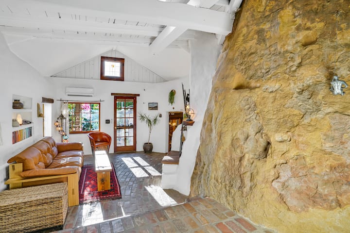 Dhoma e ndenjjes, me gurin që ne e quajmë "Big Mama". Divan lëkure me kokërr të lartë dhe tavolinë kafeje vendase artizanale.