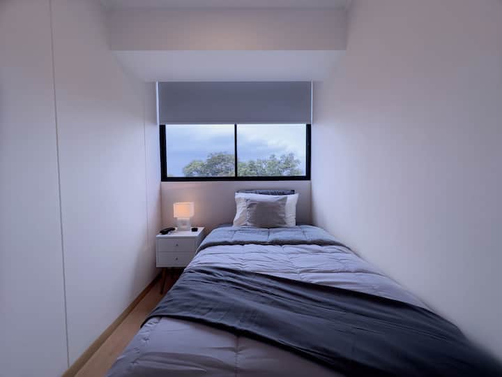 Dhoma 2 me një krevat 1 e gjysmë katror, me dollap dhe rafte për pallto, drita të ngrohta dhe perde të zezë