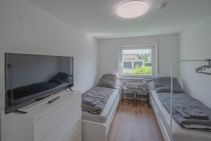 Chambre avec deux lits simples, TV et une commode