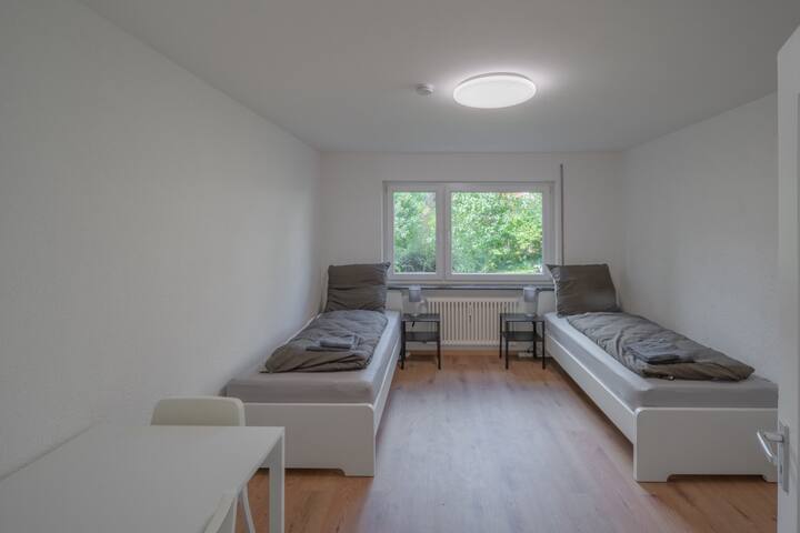 Chambre avec deux lits simples, TV et une commode
