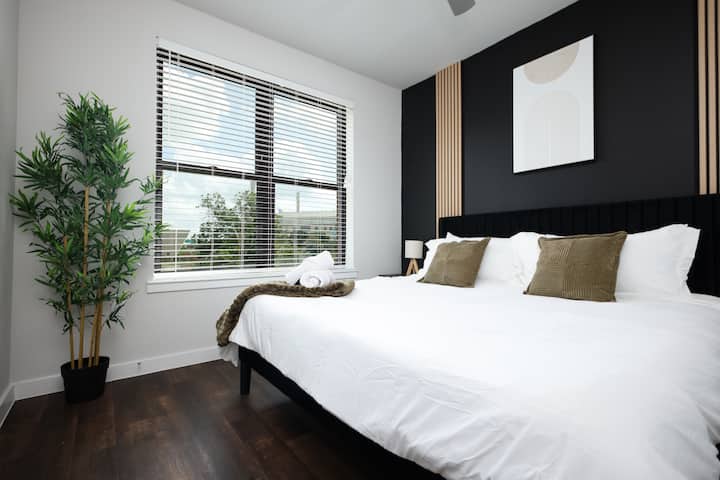 Descansa tranquilo en nuestro dormitorio sereno con una cama tamaño king, una gran ventana y una tranquila planta de bambú.