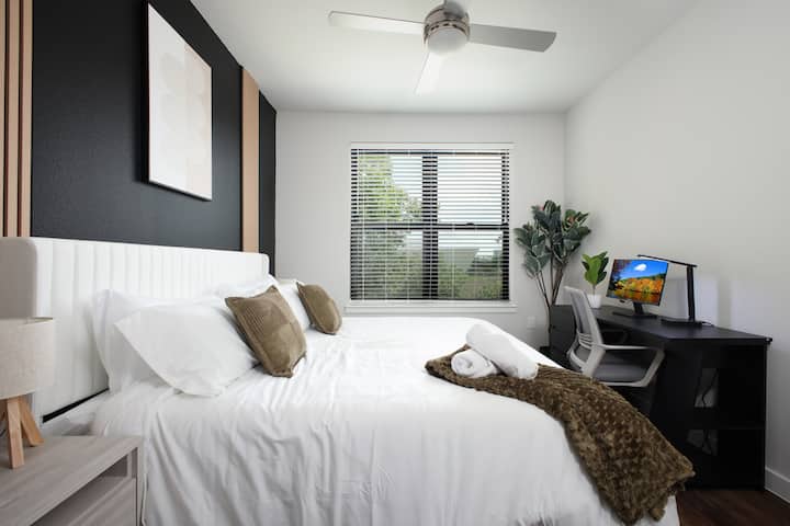 Relájate en un dormitorio sereno con una cama tamaño king, una ventana grande y un área de escritorio perfecta para trabajar o relajarse.