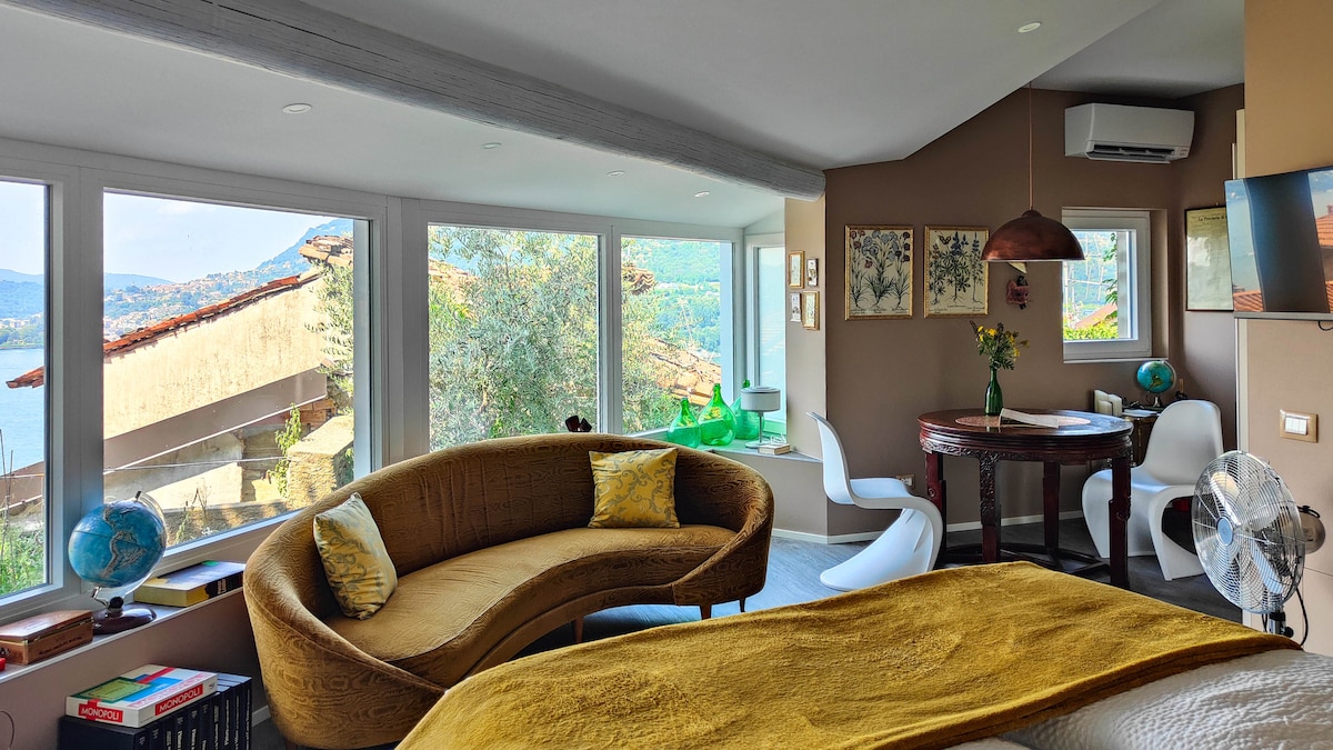 Mix di modernità e vintage nell'appartamento con giardino privato a Blevio: divano retrò in velluto, tavolo elegante in legno e sedie anni '60 per un relax totale sul Lago di Como, perfetto per serate intime.