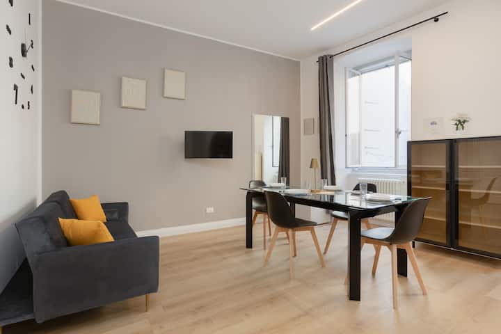 Grand salon avec coin salon, cuisine et salle à manger. Les grandes fenêtres rendent la pièce très lumineuse.