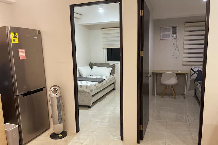 Vista de dos acogedoras habitaciones, cada una equipada con aire acondicionado y cómodas camas. El diseño compacto y funcional incluye un refrigerador cercano, por lo que es fácil almacenar aperitivos y bebidas. Perfecta para familias o grupos pequeños.