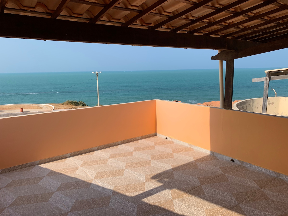 A spacious terrace is highlighted, featuring tiled flooring and a sturdy roof. The view overlooks the ocean with clear blue waters extending to the horizon, creating a sense of openness and tranquility.