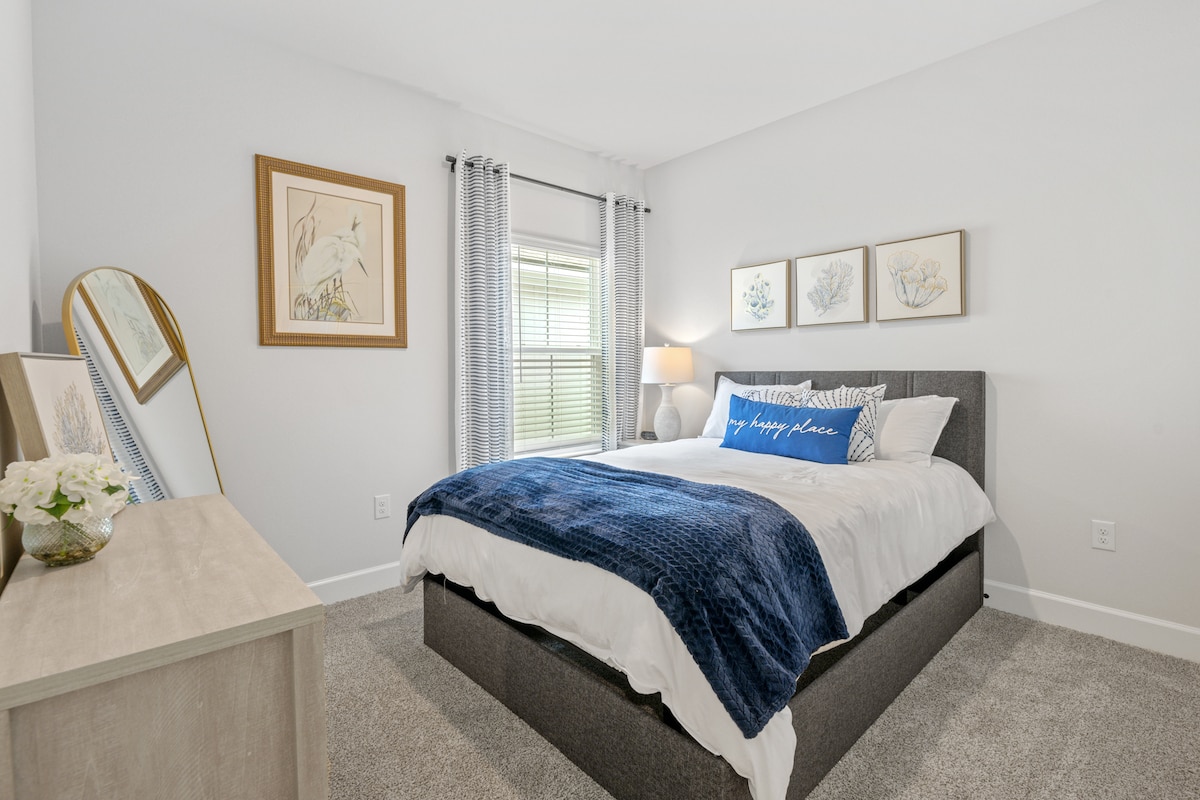 Encantador dormitorio con una acogedora cama tamaño queen y un espejo de cuerpo entero, creando un ambiente espacioso y acogedor para una estadía tranquila