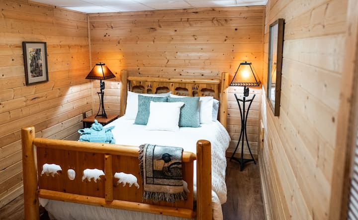 Dette soveværelse med queensize-dobbeltseng ligger nedenunder med et vindue til verandaen og fjernsynet.