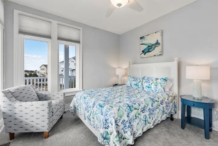 Queen bedroom with private wrap around deck, sunset and sound views, and beautiful natural light. Closet, amoire, and mounted television.
