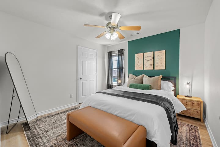 This bedroom features plush bedding and a stylish standing mirror, creating a cozy and elegant space for relaxation and reflection.