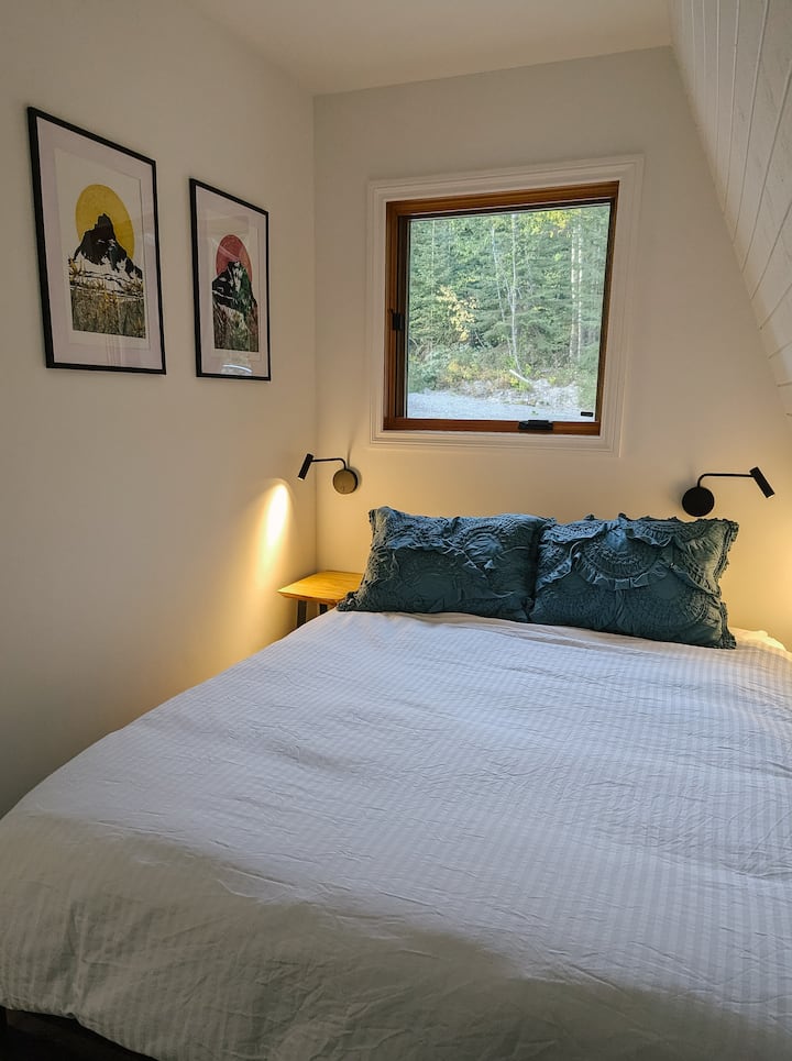 Útulná manželská posteľ s miestnymi umeleckými dielami, ktoré zdobia steny