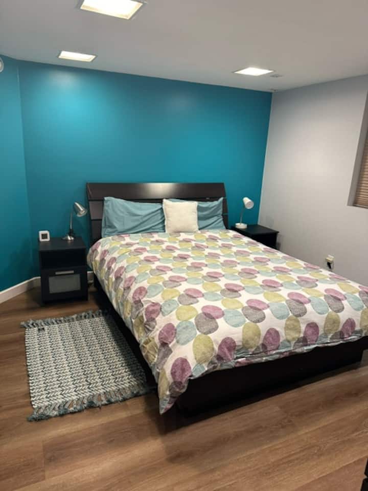 Спалня 1: Сутерен. Двойно легло. Огледало и мивка. Поставка за дрехи и чекмеджета. Бюро и стол. Баня в общо помещение в мазето.