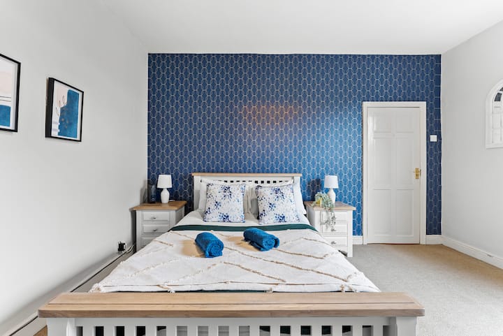 Une chambre élégante avec un mur d'accent à motifs bleus audacieux, ajoutant une touche vibrante à l'espace moderne et aéré.