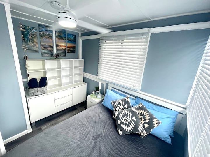Segundo dormitorio con una cama tamaño queen y TV.