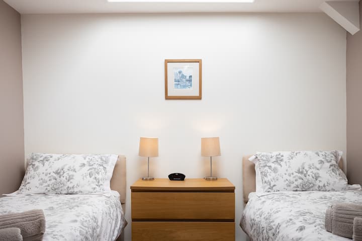 Dvojlôžka s oddelenými posteľami so zásuvkami, dvoma lampami a vstavaným šatníkom.