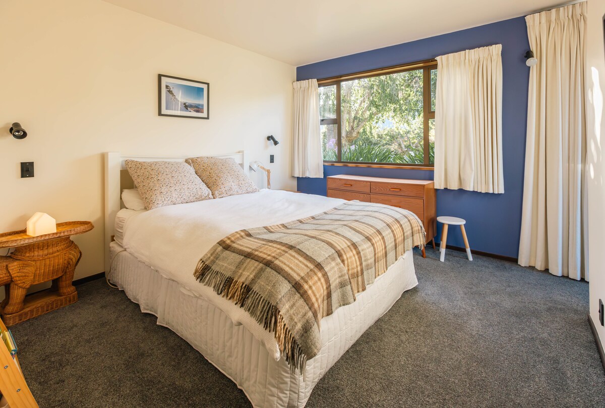 ห้องนอนกว้างขวางพร้อมเตียงควีนไซส์แสงแดดสวยและวิวภูเขาและสนามหญ้าด้านหน้า