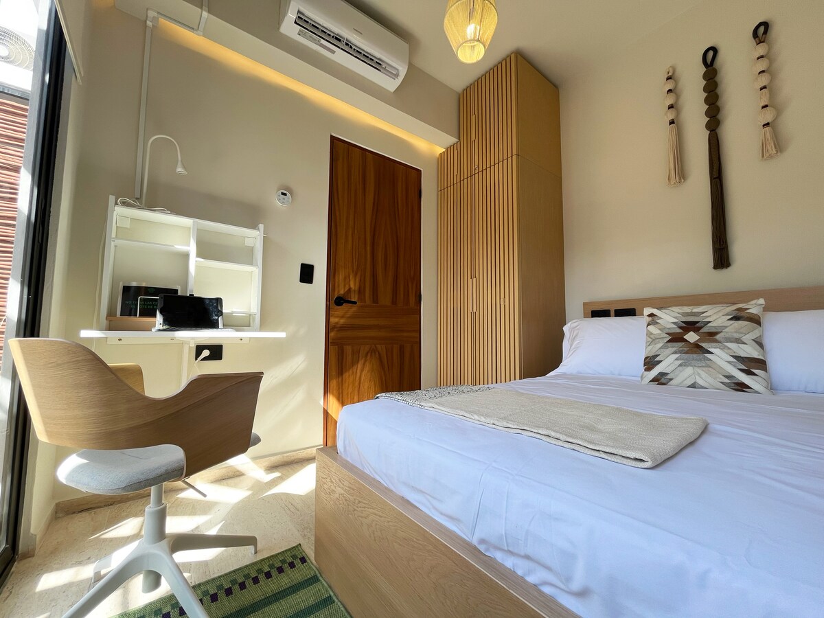 Naša spavaća soba s bračnim krevetom nudi luksuznu udobnost s udobnim krevetom s vrhunskom posteljinom. Veliki ormar i zidni ukrasi od makramea u kombinaciji s blagom noćnom rasvjetom odražavaju topao, očaravajući sjaj Tuluma.