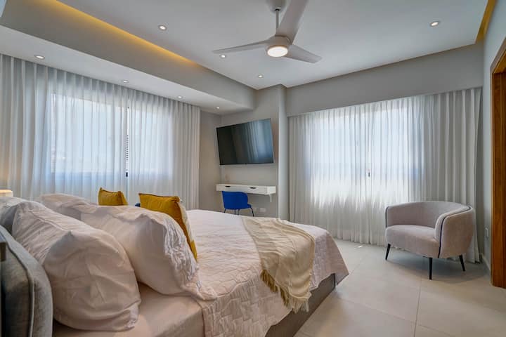 חדר השינה המדהים כולל מיטת קינג מפוארת, מזרן יוקרתי, מזגן, מאוורר תקרה, וילונות שחורים, אורות אווירה, ארון מרווח, טלוויזיה חכמה, שולחן כתיבה, נוף יפה לעיר וחדר רחצה צמוד יוקרתי עם מקלחת גשם.