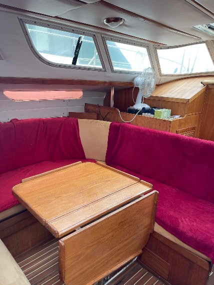 A comfortable seating area is featured, with a wooden table surrounded by plush red upholstery. Large windows allow natural light to fill the space, and wooden accents enhance the overall warmth of the interior.