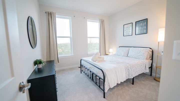 ห้องนอนที่เงียบสงบและน่าอยู่พร้อมเครื่องนอนที่อบอุ่น แสงไฟที่นุ่มนวล และความรู้สึกทันสมัยที่สะอาด เหมาะสำหรับการผ่อนคลายและการพักผ่อนยามค่ำคืนที่ยอดเยี่ยม