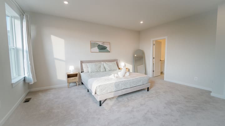 ห้องนอนที่เงียบสงบและน่าอยู่พร้อมเครื่องนอนที่อบอุ่น แสงไฟที่นุ่มนวล และความรู้สึกทันสมัยที่สะอาด เหมาะสำหรับการผ่อนคลายและการพักผ่อนยามค่ำคืนที่ยอดเยี่ยม