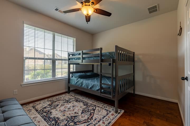 غرفة النوم الثالثة: مثالية للعائلات! تتميز بسرير بطابقين كاملين (يتسع لأربعة أشخاص) وسرير أريكة لترتيبات نوم مرنة. تشمل أرضيات خشبية صلبة عالية الجودة ومروحة سقف.