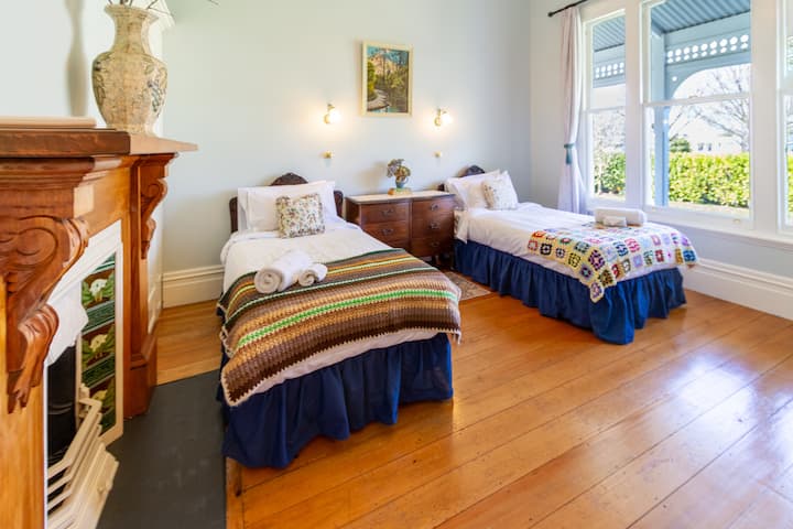 dhomë gjumi me ndjesi të ngrohtë me 2 mbulesa krevati dhe jastëkë tekë shtojnë një nuancë ngjyrash dhe tekstesh. Vetëm oxhak dekorativ