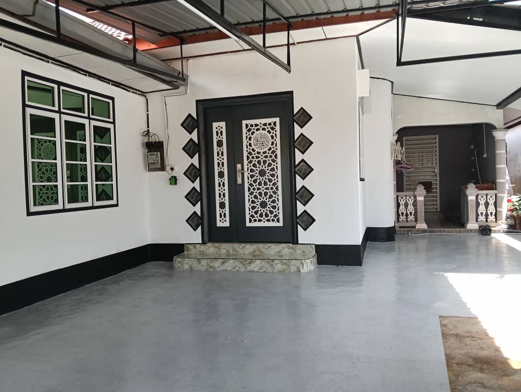 An entrance area is visible, featuring a decorative door framed by intricate patterns. Symmetrical green windows provide natural light, contrasting with the white walls. The flooring is smooth and grey, enhancing the spacious feel of the entryway.