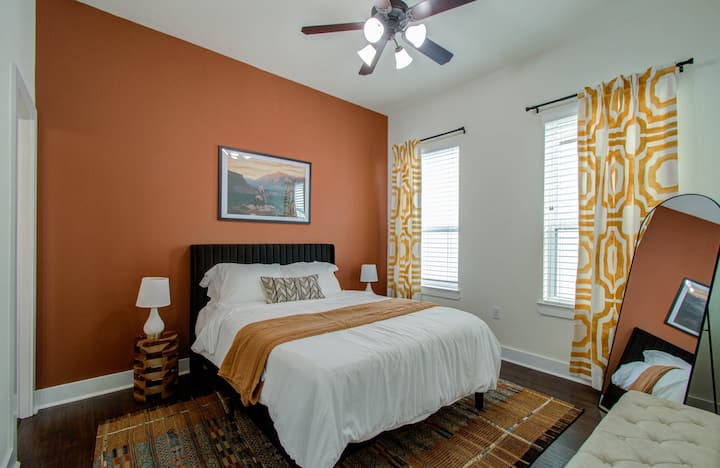 Spálňa s manželskou posteľou, stropným ventilátorom a štýlovým stojacim zrkadlom vytvára príjemnú a elegantnú atmosféru.