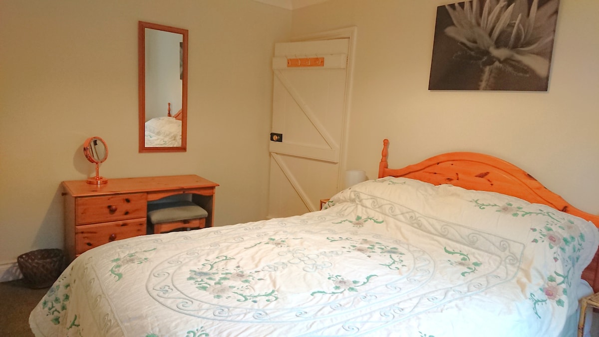 The bedroom at the rear has a double bed with orthopaedic mattress, two bedside tables with touch lamps, two wardrobes, dressing table with make-up mirror and hairdryer, secondary double glazing overlooking the hill behind and electric heating. 