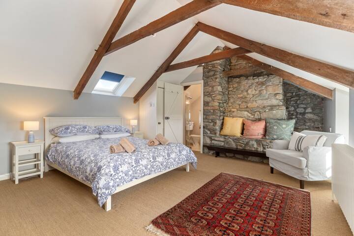 キッチン/ダイニングルームから2つの寝室がある1階まで階段を上ります。 こちらはベッドルーム1で、キングサイズベッドとシャワー、トイレ、洗面台を備えた専用バスルームがあります。