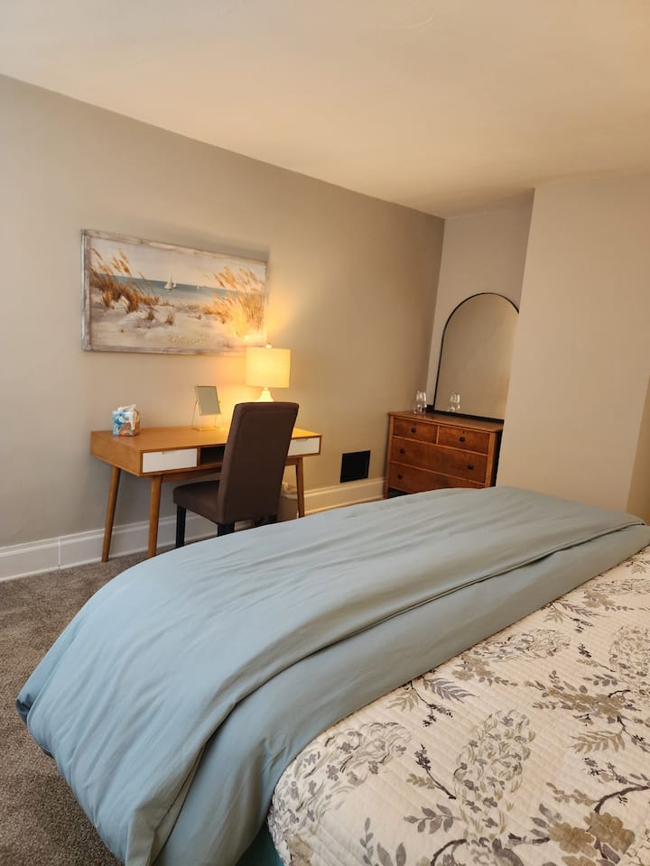 غرفة نوم بسرير كينج في الطابق الثاني.  تحتوي غرفة النوم هذه على مكتب ومكتب ومروحة طاولة.  يوجد خزانة ملابس ومساحة تخزين إضافية ومساحة لتعليق الملابس في الخزانة.  تحتوي هذه الغرفة على رف أمتعة لحمل الحقائب