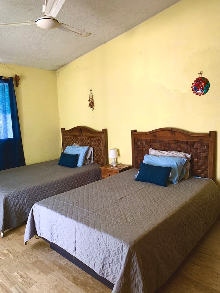 Primer dormitorio ubicado arriba con aire acondicionado y ventilador. También hay acceso al balcón desde una puerta corrediza. 