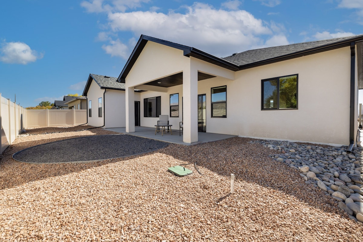 An outdoor patio area is highlighted, featuring a seating arrangement with two chairs placed on a concrete surface. Gravel landscaping surrounds the space, and a low fence is visible in the background, providing a sense of privacy.