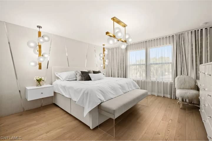 Dormitorio principal con colchón tamaño king con la parte superior acolchada, mesitas de noche flotantes, amplio espacio de almacenamiento en el cajón de ropa, banco personalizado, área de tocador designada o escritorio para computadora portátil/oficina, accesorios de ventanas opacas con control remoto y TV inteligente de 55 pulgadas.