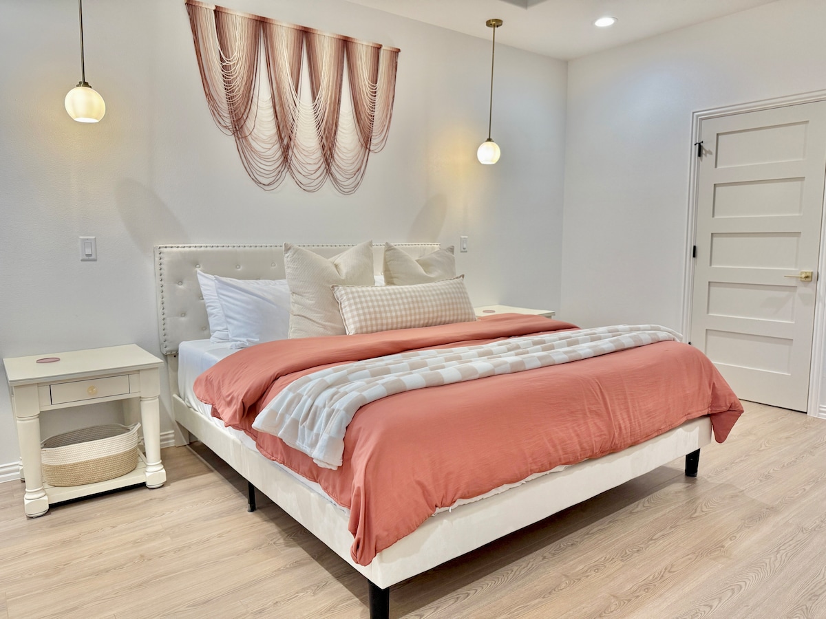 Step into the dreamy master bedroom featuring a cozy king-sized bed adorned with plush pink blankets and a soft white throw blanket. This serene space is perfect for unwinding after a day of fun, inviting you to snuggle in and enjoy your stay!