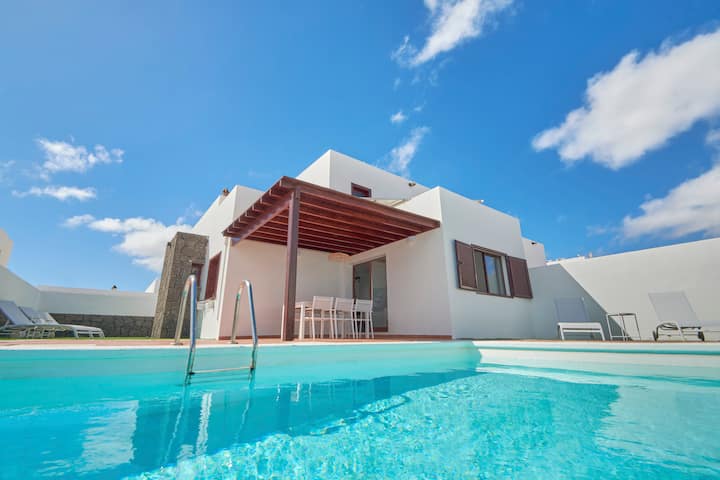 Vista de la piscina con tumbonas y porche en Casa Nolva