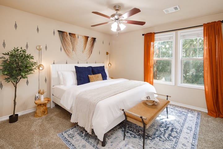 Rust uit in de slaapkamer met een zacht kingsize bed, aangevuld met grote ramen met elegante gordijnen voor een gezellig en sereen toevluchtsoord.