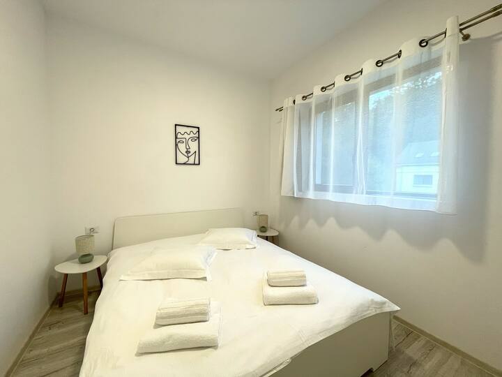 Första sovrummet i huset erbjuder en dubbelsäng som har vita rena bomullssängkläder tillsammans med mysiga kuddar och fräscha handdukar, elegant väggdekoration, trägolv, höghastighetsinternet och tillgång till uppvärmning för kalla vinterdagar