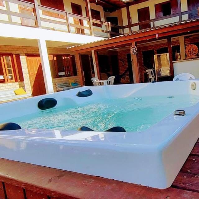 A relaxing jacuzzi is positioned on a wooden deck, surrounded by a spacious outdoor area. The inviting water surface reflects natural light, while the surrounding architecture features multiple balconies and windows, creating a welcoming atmosphere for leisure.