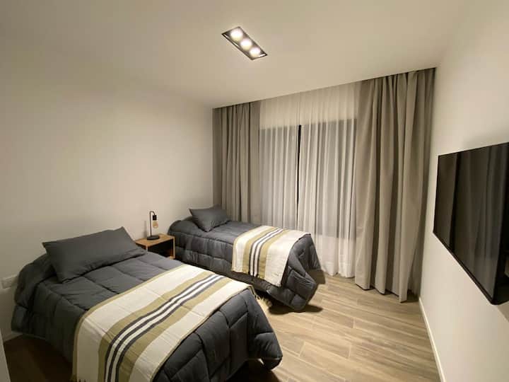 Спална соба со поглед кон градината и планинските венци. Сомиерс (2) од 0,80 x 1,90 или двоен кревет 1,60  x 1,90м. Сосема нови перници и постелнина. AA студ/топлина.
Двојни завеси газа/затемнување. Плакетата  е завршена.
Паметен телевизор 42 инчи.
Ноќна масичка со ламба.