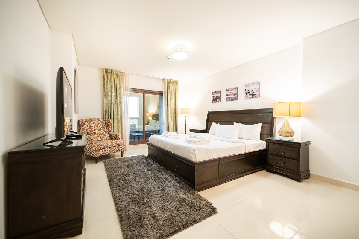 غرفة نوم واسعة في نخلة جميرا Airbnb – سرير كينج وسجادة مريحة وإمكانية الوصول إلى الشرفة لقضاء ليلة مثالية.