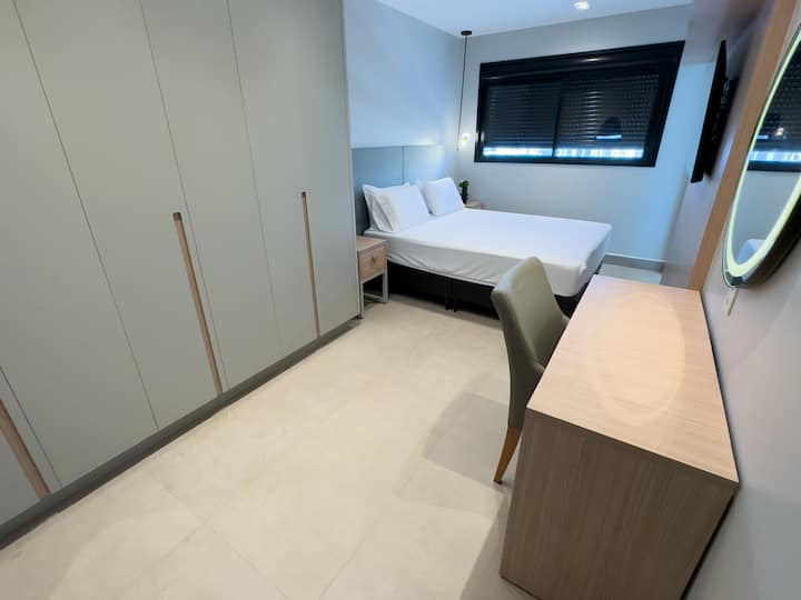 Suita kryesore me krevat dopio "Queen" dhe pranë krevatit me 4 jastëkë dhe shtroja të plota, smartv 50"Qled, ajër të kondicionuar me inverter pa erë 12000bts, pasqyrë trupi në mur, 2 shërbëtorë dhe 3 dollapë me sirtarë, pastrues këpucësh dhe komodinë. 